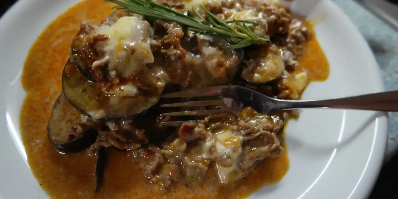 Herzhafte Auberginen-Hackfleisch-Auflauf, inspiriert von Omnia Rezepte, mit geschmolzenem Käse und Rosmarin garniert.