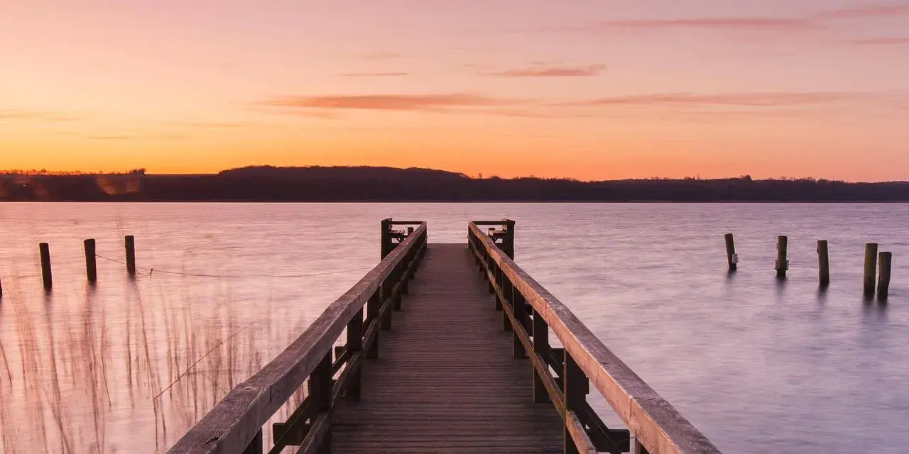 Holzsteg am See bei Sonnenuntergang, ein idyllischer Ort für Badeseen Schleswig-Holstein.