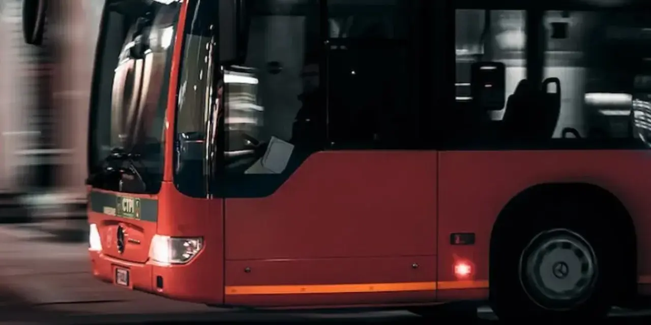 Czerwony autobus w ruchu miejskim, widok z przodu i z boku.