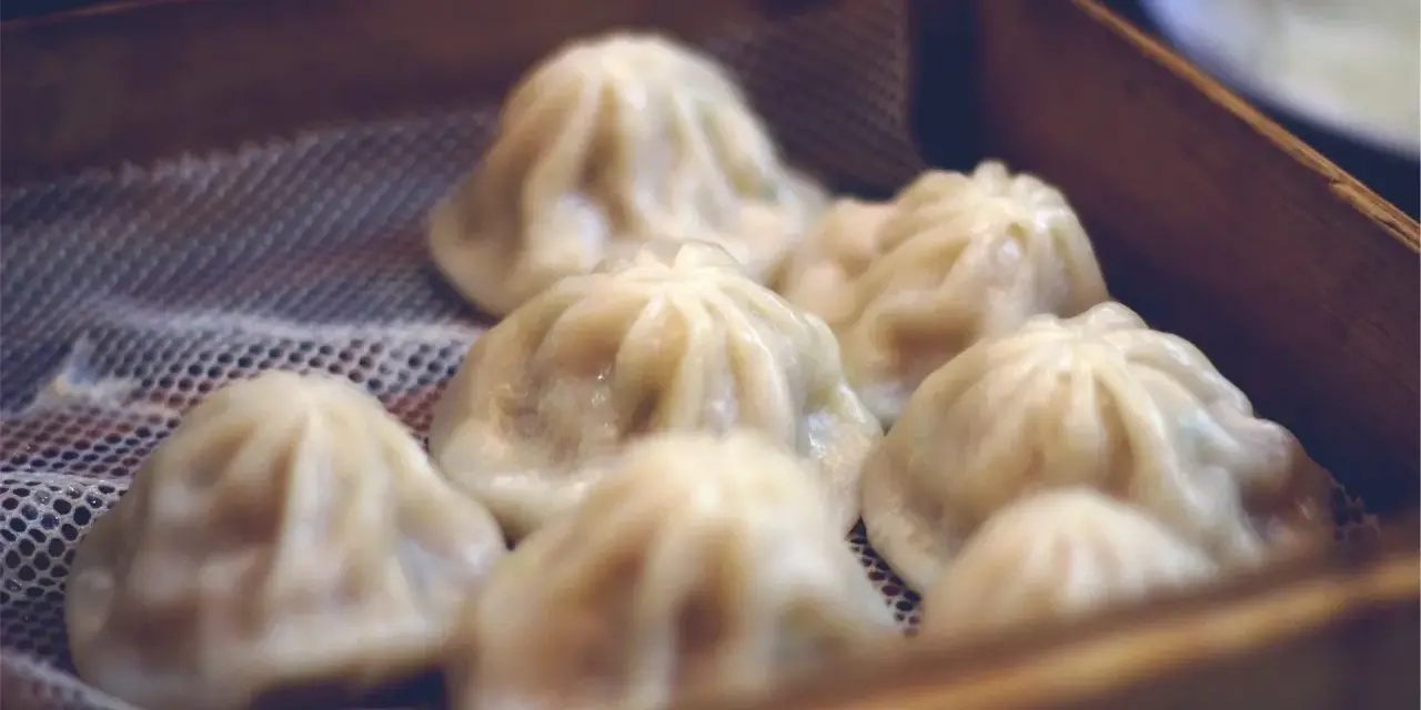 Pyszne, parujące dim sum w bambusowym koszyku. Delikatne pierożki kuszą swoim wyglądem.