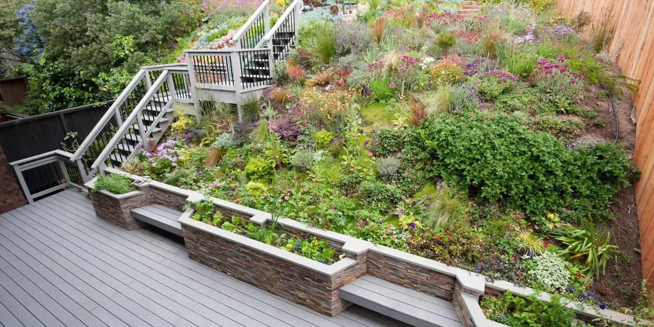 Magnifique aménagement talus raide avec escalier, terrasses et jardinières fleuries. Un jardin luxuriant et coloré.