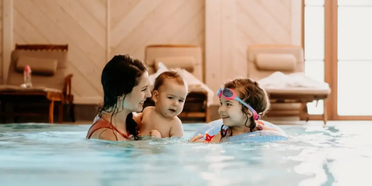 Rodzina cieszy się basenem w hotelu dla dzieci w Wiśle. Mama z dwójką dzieci pluska się w wodzie, tworząc radosne wspomnienia.