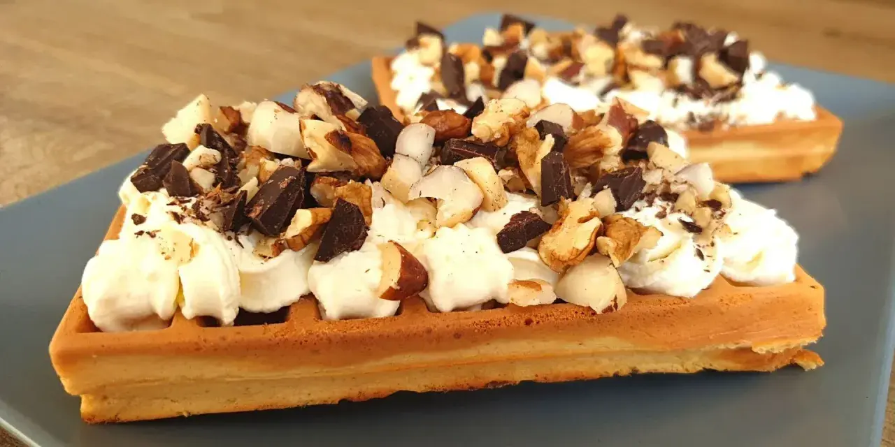 Dwa keto gofry z mascarpone, udekorowane kawałkami czekolady i orzechów. Idealne na deser.