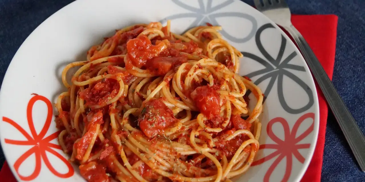 Pyszne spaghetti napoli przepis na talerzu, z sosem pomidorowym i ziołami. Idealne danie dla miłośników włoskiej kuchni.