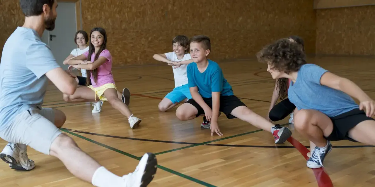Un entraîneur guide des enfants lors d'une séance d'étirements. L'accueil des mineurs dans cette association sportive est une priorité.