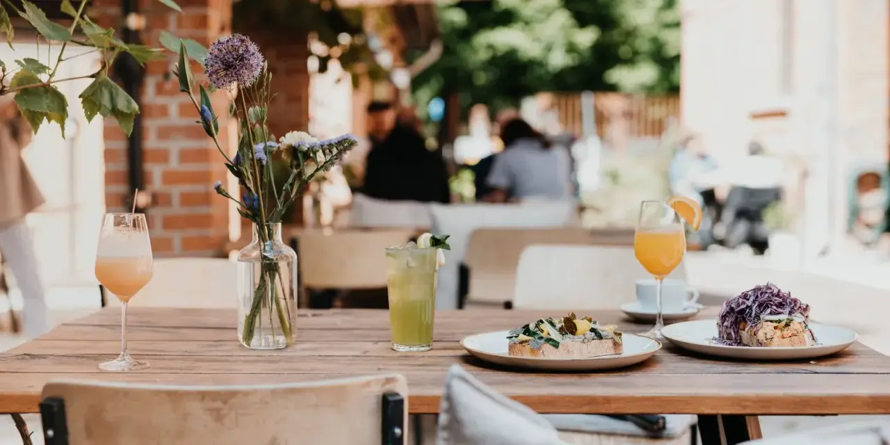 Leckeres Frühstück im 21 gramm Berlin: Toast mit Belag, Drinks & Blumen auf Holztisch.
