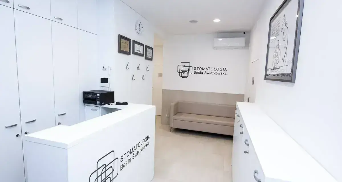 Nowoczesne wnętrze recepcji gabinetu stomatologicznego z kanapą i logotypem.