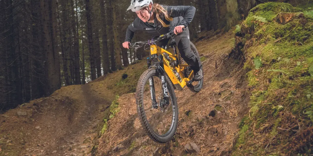A mountain biker navigates a steep, wooded trail, showcasing the thrill of downhill mtb trails.