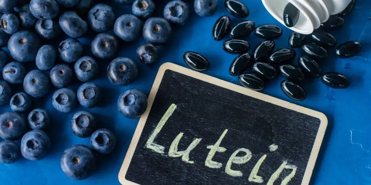 Borówki i kapsułki suplementu diety. Na tabliczce napis "Lutein". Luteina na co? Na zdrowie oczu!