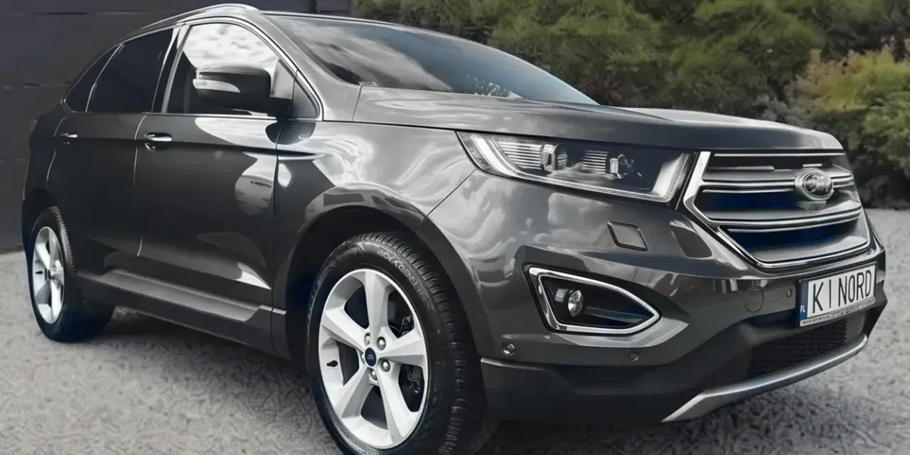 Ford Edge 2.0 TDCI w ciemnoszarym kolorze, zaparkowany przed garażem. Oferta leasingu i kredytu.