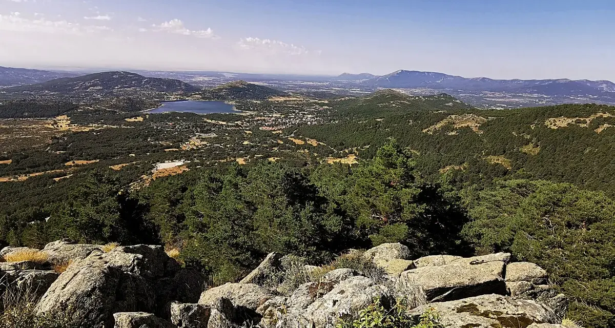 Vista panorámica del valle de la barranca, con un lago azul y montañas verdes bajo un cielo despejado.