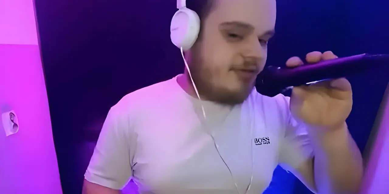 Młody dj akun w słuchawkach i białej koszulce z mikrofonem w ręku, w studiu z fioletowym oświetleniem.