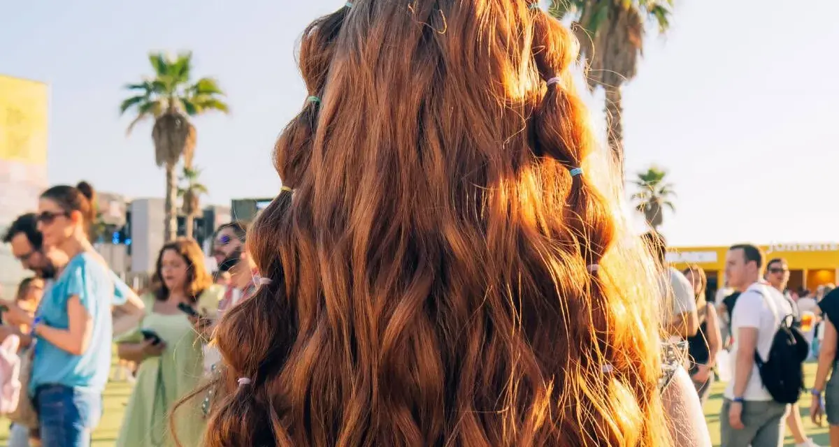 Peinados para festivales: cabello largo y ondulado con secciones recogidas en pequeñas coletas, ideal para disfrutar del sol y la música.