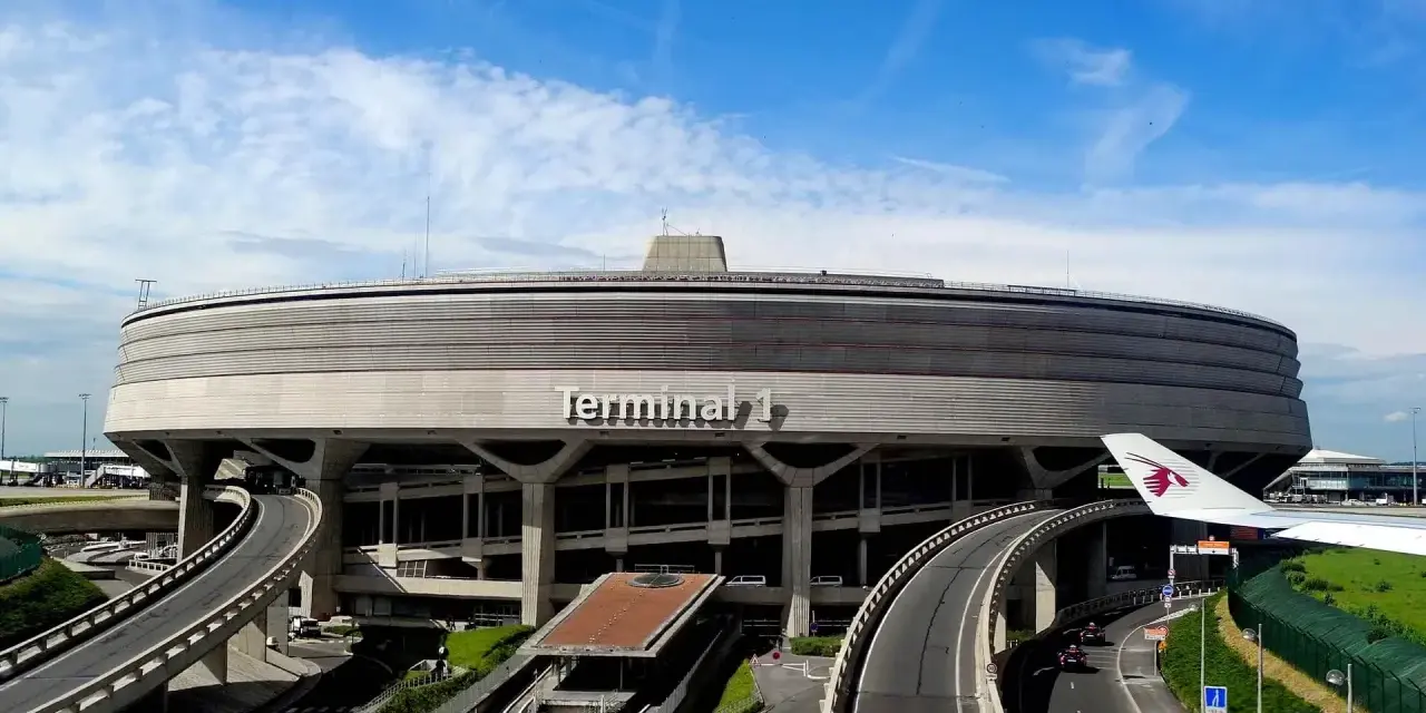 Charakterystyczny Terminal 1 na lotniskach w Paryżu, z krętymi drogami i skrzydłem samolotu.