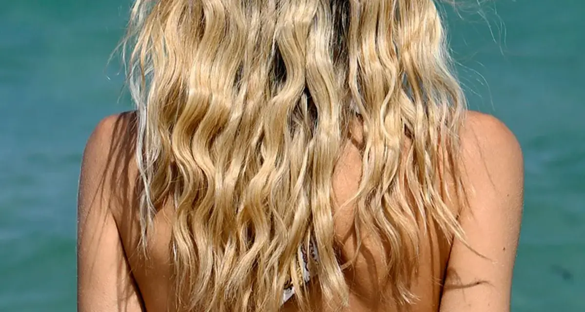 Blondes Haar mit Beach Waves im Meer. Die Sonne scheint auf die Schultern.