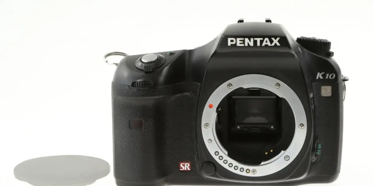 Czarny aparat Pentax K10 z widocznym mocowaniem obiektywu i osłoną. Wewnątrz widoczny jest sensor ccd.