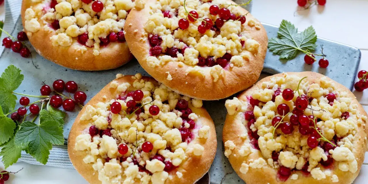 Vier kleine Küchlein mit Streuseln und roten Johannisbeeren, die den köstlichen jostabeere geschmack versprechen.