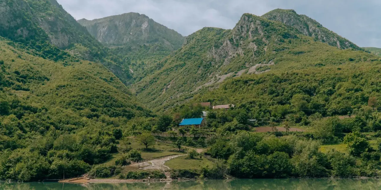 Zielone góry nad jeziorem, z domami i niebieskim dachem.