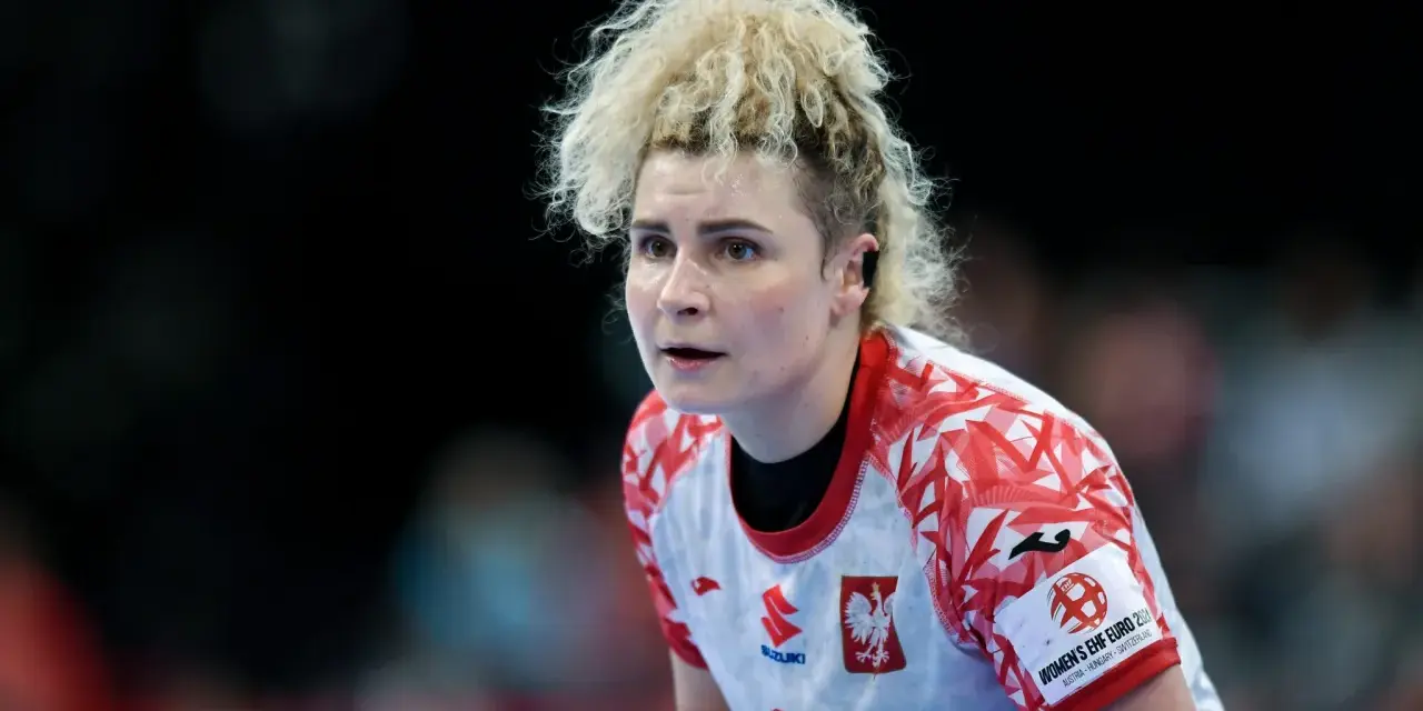 Sylwia Matuszczyk, zawodniczka w białej koszulce z czerwonymi wzorami, skupiona na boisku.