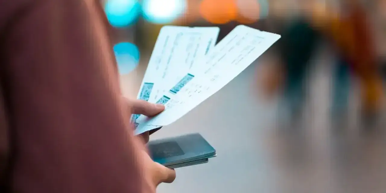 Dłoń trzyma bilety lotnicze i paszport. Może to być sytuacja związana z planowaniem podróży lub procesem **Ryanair zwrot biletu**.