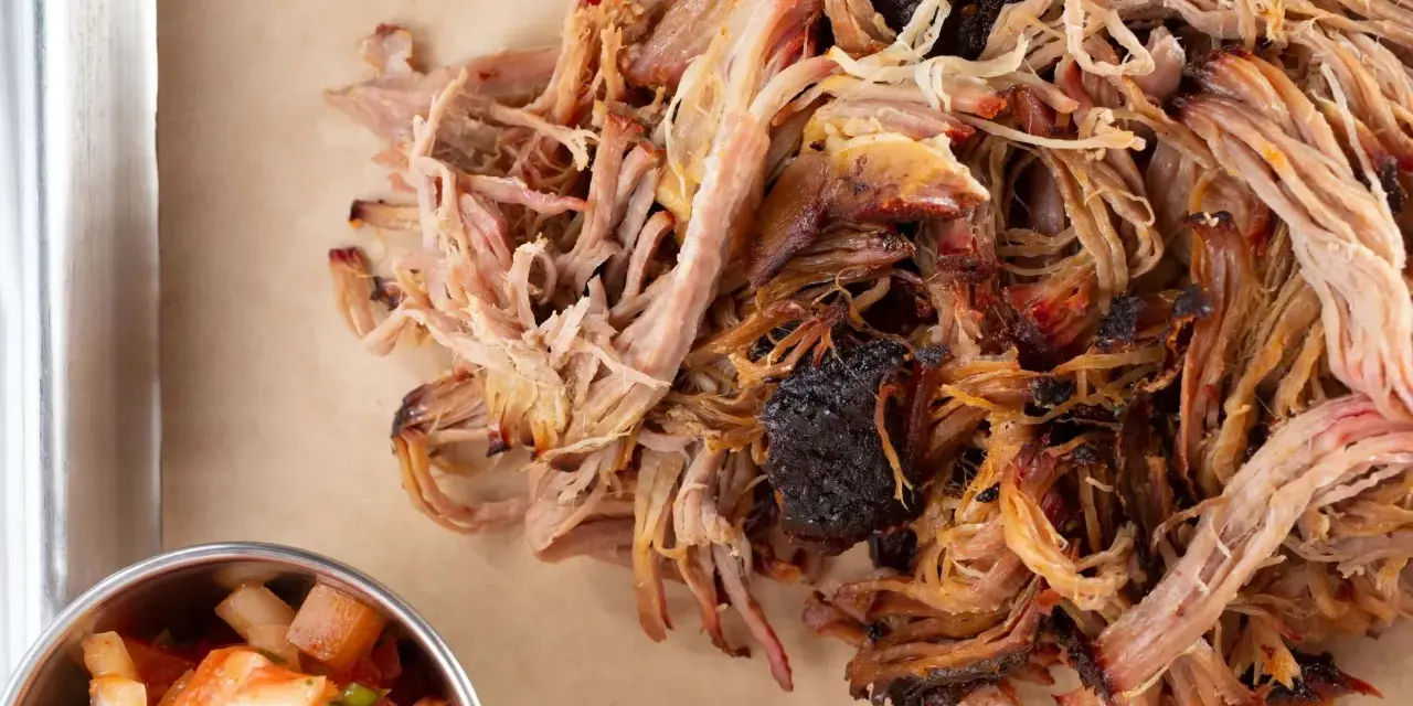 Zartes Pulled Pork, perfekt gegart, zeigt die ideale pulled pork kerntemperatur. Daneben eine Schale mit frischer Salsa.