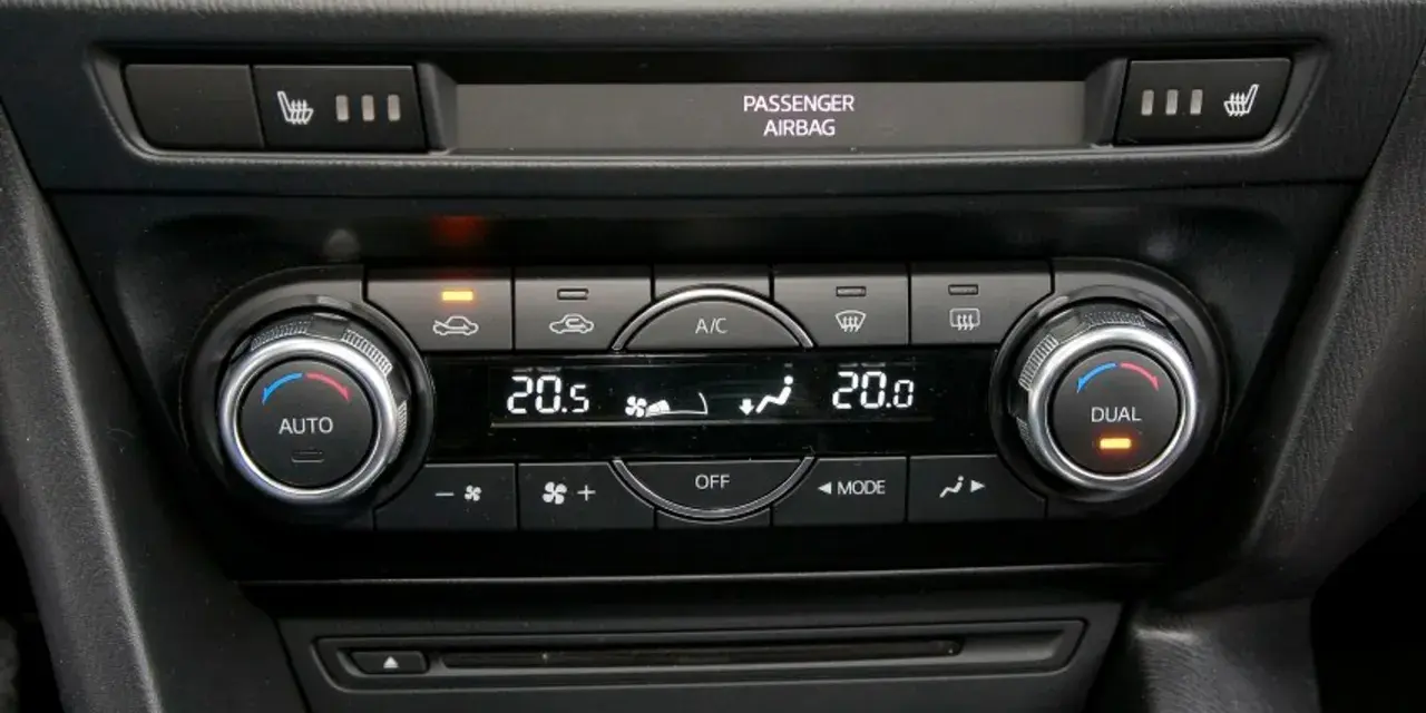 Panel sterowania klimatyzacją w samochodzie, z pokrętłami AUTO i DUAL, wyświetlaczem temperatury 20.5°C i ikonami nawiewu. Idealny do ozonowania klimatyzacji.
