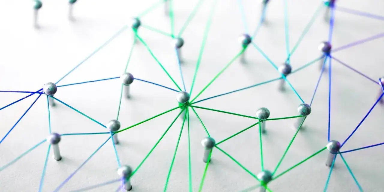Netzwerk aus silbernen Pins und bunten Fäden auf weißem Untergrund.