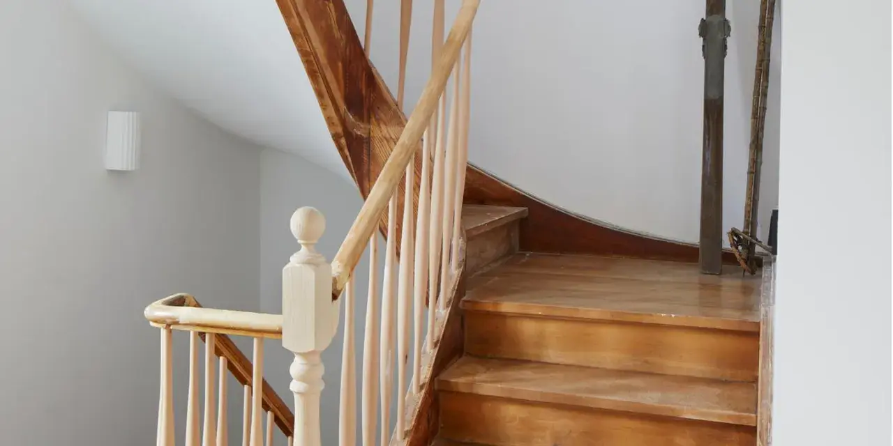 Eine alte Holztreppe wartet auf ihre Renovierung. Die Stufen und das Geländer aus hellem Holz zeigen Gebrauchsspuren, bereit für ein neues Leben.