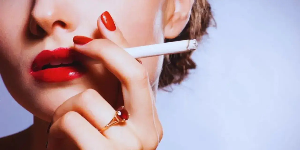 Labios rojos, uñas rojas y un cigarrillo. Una mujer se lleva el cigarrillo a la boca, quizás pensando que la nicotina adelgaza.