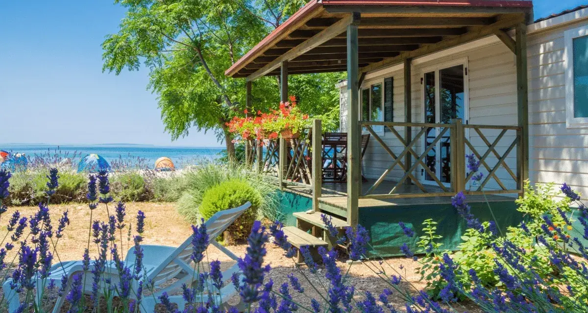 Idealne miejsce, gdzie na wakacje z dziećmi: domek letniskowy blisko plaży, z leżakami i kwitnącą lawendą.