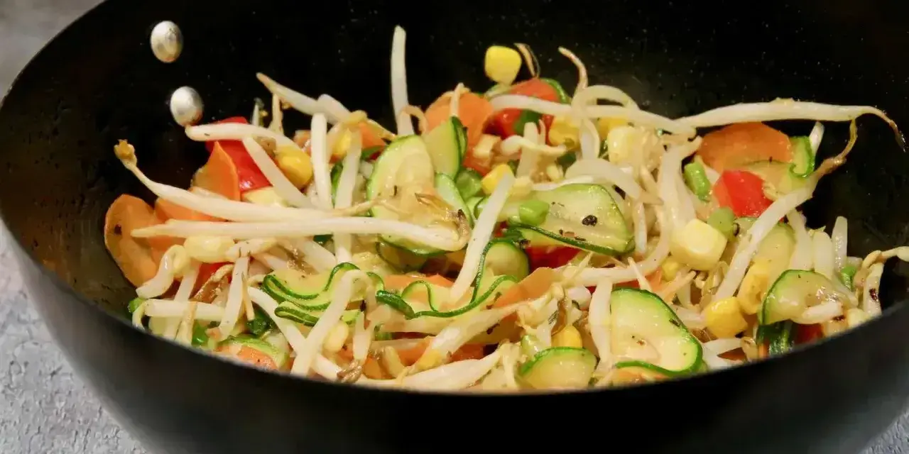 Kolorowe warzywa teriyaki w woku: kiełki fasoli mung, cukinia, marchewka, papryka i kukurydza.