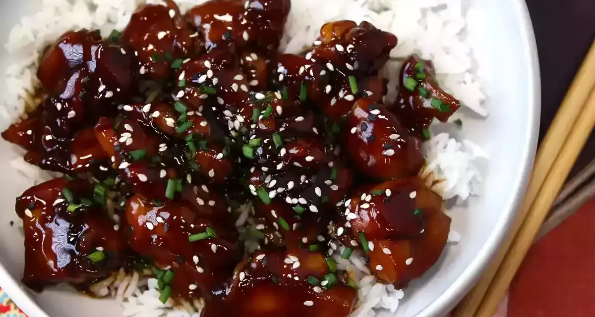 Aksamitny teriyaki kurczak w sosie, posypany sezamem i szczypiorkiem, podany na białym ryżu. Pyszne danie gotowe do spożycia.