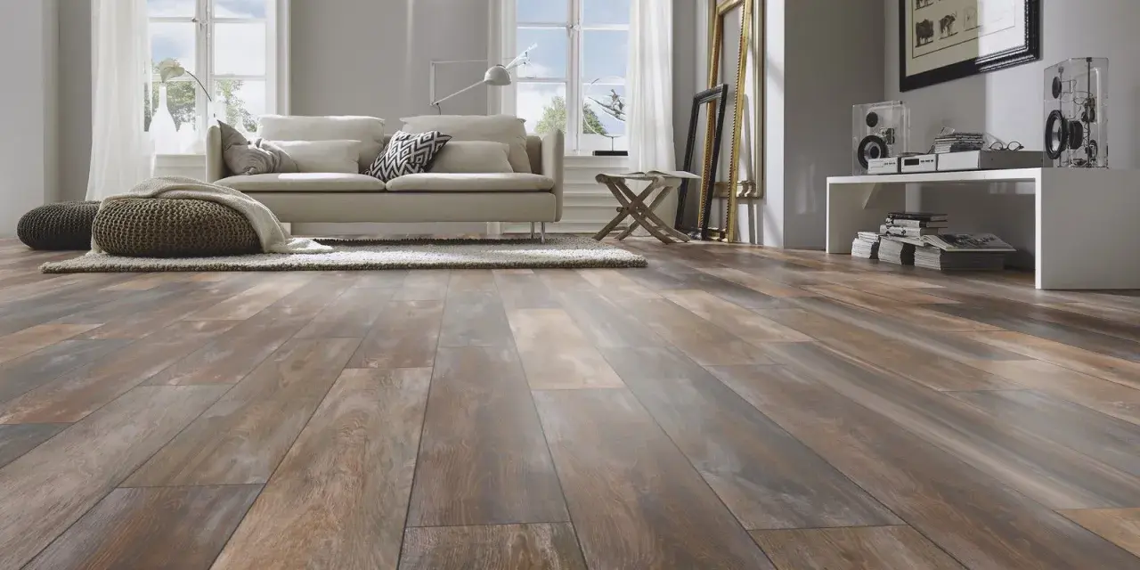 Sala de estar moderna con suelo de tarima AC5 de aspecto madera desgastada, sofá beige, alfombra y pufs.