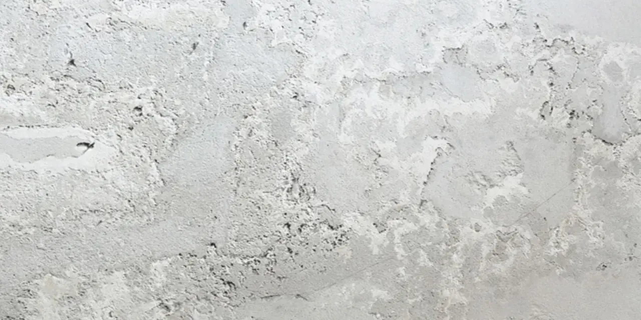 Textura de pared con manchas blancas y grises, como si la pintura se estuviera descascarando.