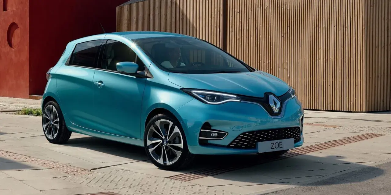 Błękitny Renault Zoe z nowoczesnymi światłami LED stoi na tle drewnianej elewacji.
