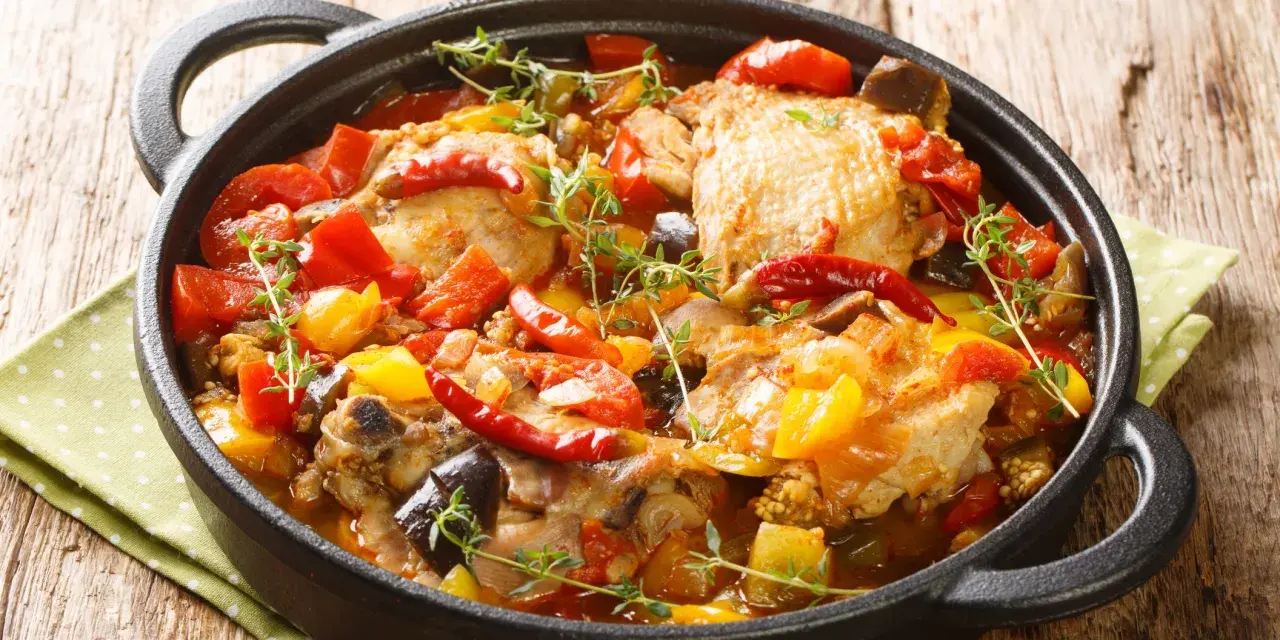 Sobracosce di pollo stufate con peperoni, pomodori, melanzane e peperoncino, guarnite con timo fresco.