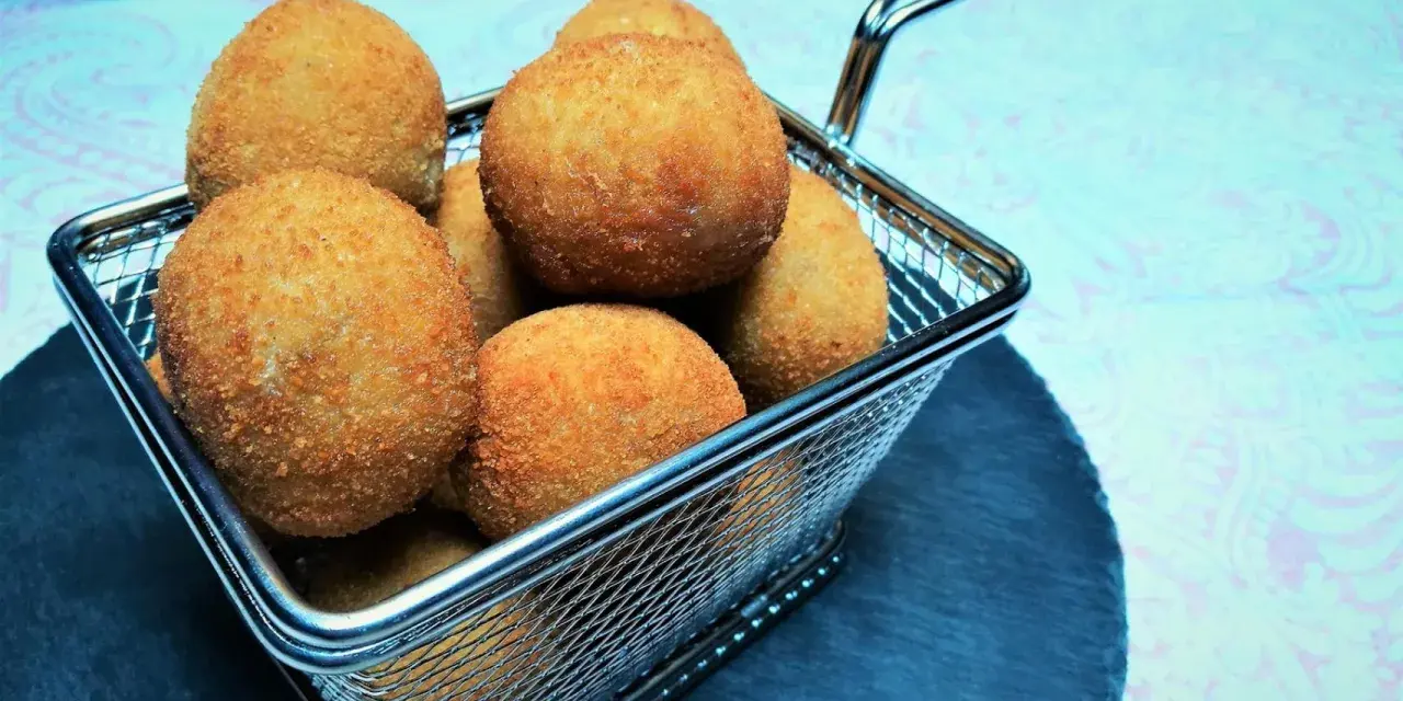 Croquetas doradas y crujientes en una cesta metálica.