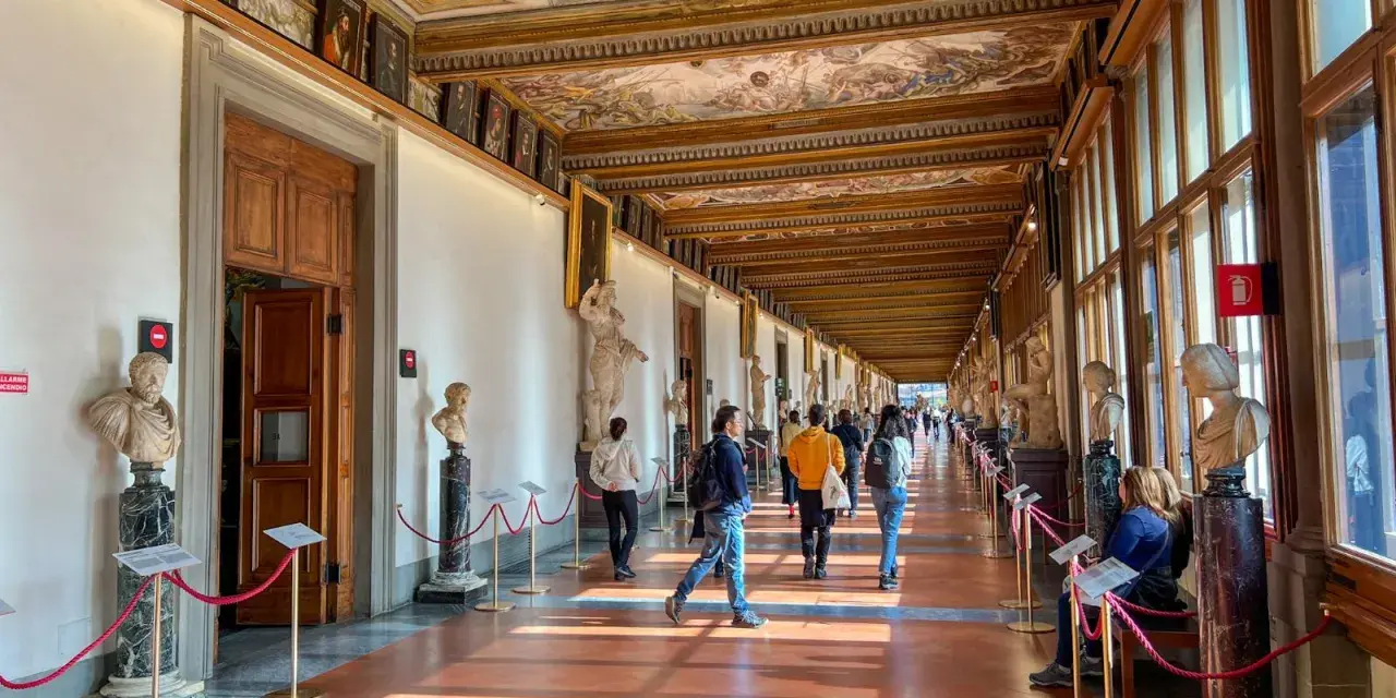 Korytarz galerii sztuki we Florencji z rzeźbami, obrazami i malowanym sufitem.