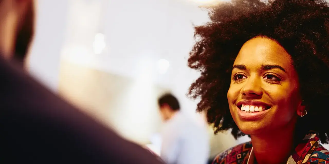 Donna sorridente in un colloquio, pensando a che lavoro fare a 40 anni senza esperienza.