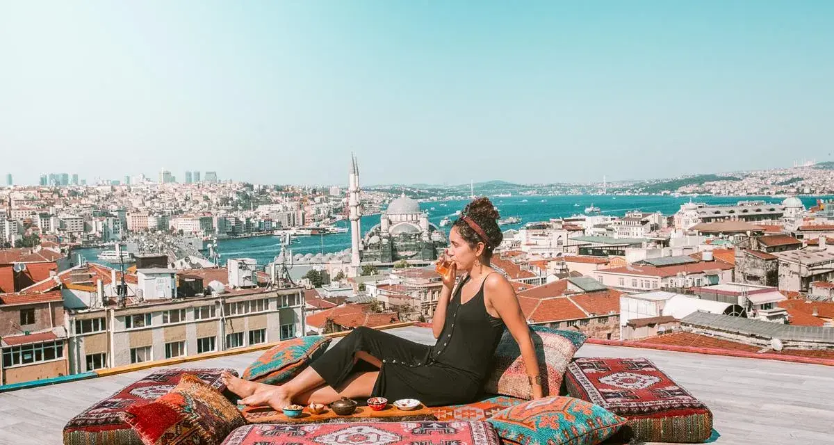 A woman enjoys a drink on a rooftop overlooking Istanbul, a scene straight out of a Rick Steves Turkey adventure.