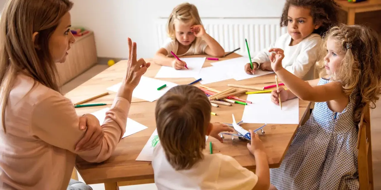 Bambini disegnano e giocano con un aereo, guidati da un'insegnante. Un esempio di come le scienze della formazione sbocchi in attività creative e formative.