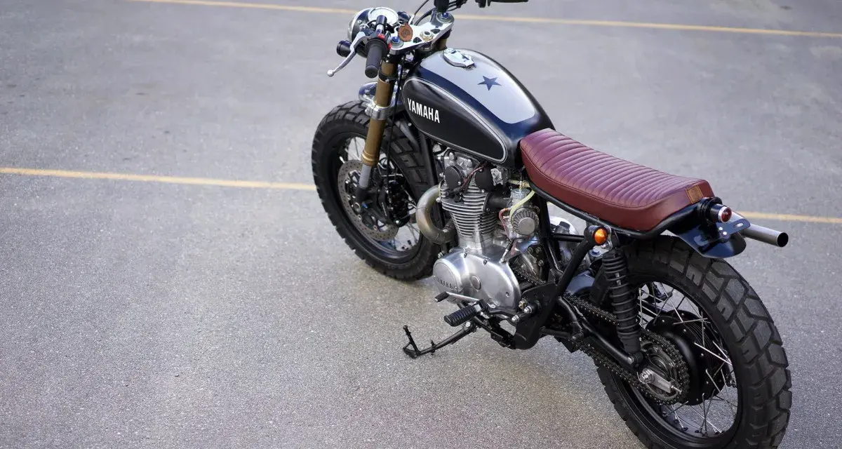 Klasyczny motocykl Yamaha z brązowym siedzeniem i gwiazdą na baku. Kraj pochodzenia tego modelu to Japonia.