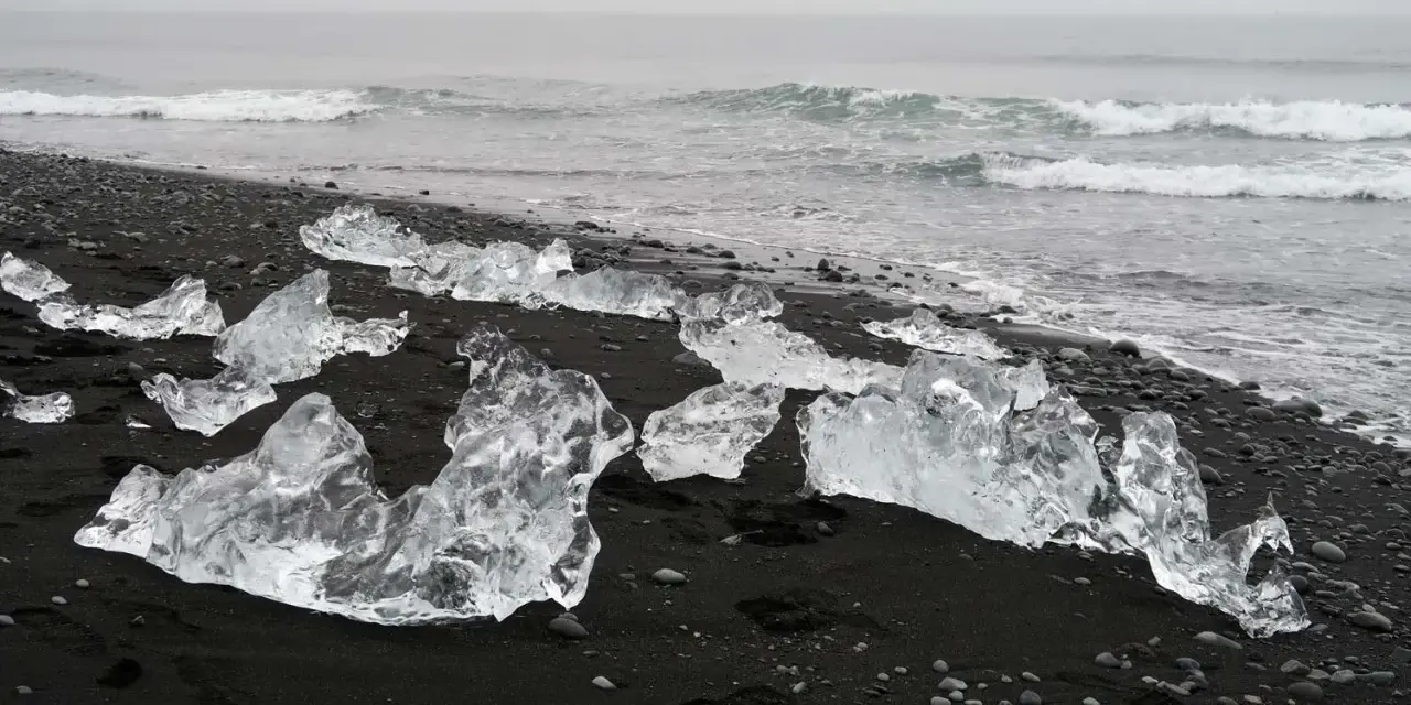 Lodowe bryły na czarnym piasku tworzą magiczną diamentową plażę Islandii. Fale oceanu delikatnie obmywają ten niezwykły krajobraz.