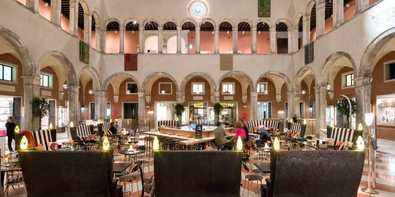 Lussuoso cortile interno con arcate, ideale per scoprire dove fare shopping a Venezia, tra negozi eleganti e aree lounge.