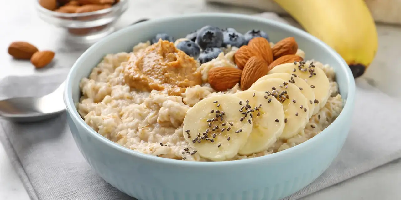 Avena cremosa con plátano, arándanos, almendras y mantequilla de maní. Una guía visual de como cocinar avena para un desayuno nutritivo.