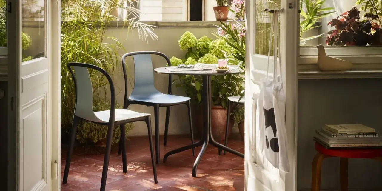 Schmaler Balkon Ideen: Gemütliche Sitzecke mit Tisch und Stühlen, umgeben von üppigem Grün. Perfekt für kleine Räume.