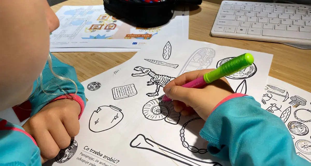 Dziecko koloruje edukacyjne karty pracy z dinozaurem i artefaktami.