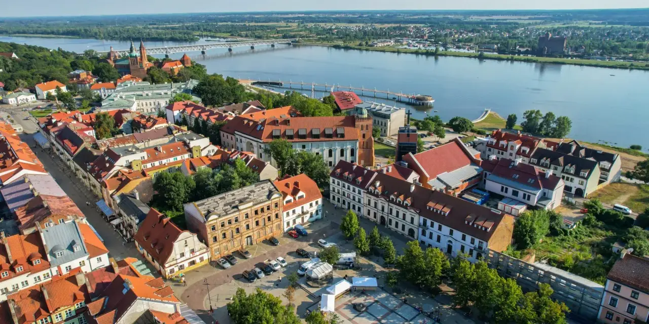 Widok z lotu ptaka na Płock, Wisłę i most. Widać zabytkowe kamienice, katedrę i rynek, które są głównymi atrakcjami w Płocku.