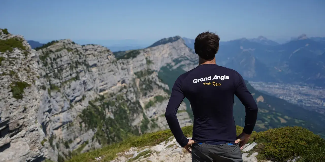 Un cycliste admire le panorama après un **tour du Vercors 7 jours**. Le paysage montagneux est spectaculaire.