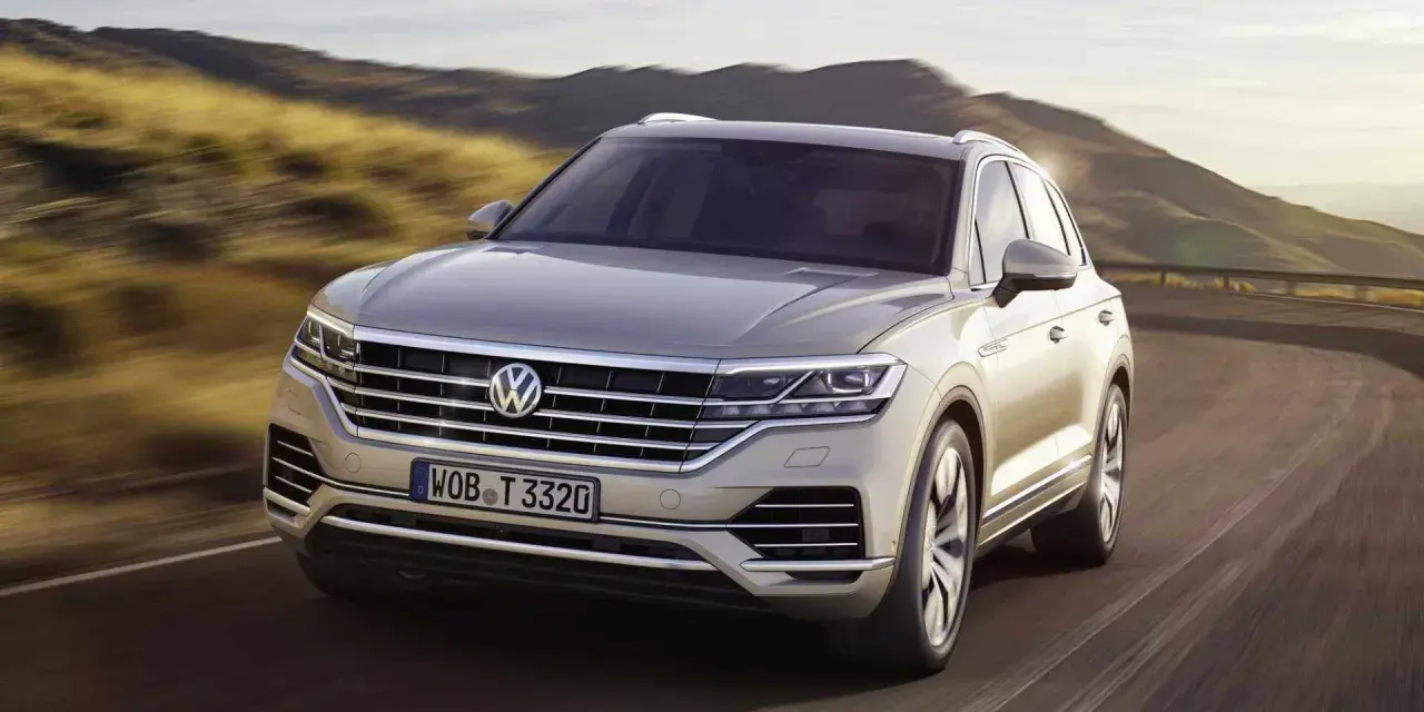 Elegancki Volkswagen Touareg, jeden z wielu imponujących volkswagen modele, pędzi po krętej drodze wśród wzgórz.
